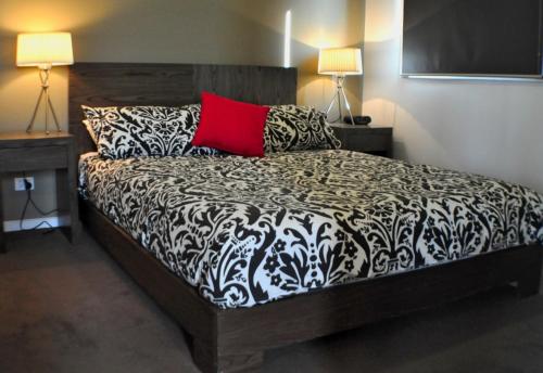a bedroom with a bed with a red pillow and two lamps at Triggerplant 3 in Dinner Plain