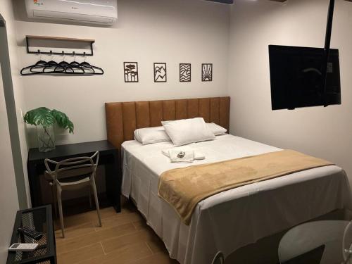 a bedroom with a bed and a desk and a tv at Suites Coliseu 40-A in Petrolina