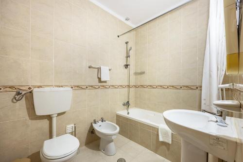 a bathroom with a toilet and a sink and a tub at Villas Brites nº4 in Burgau