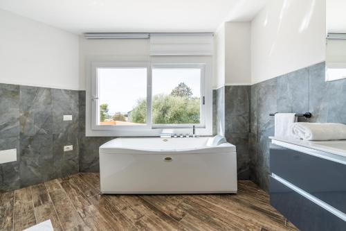 a bathroom with a white sink and a window at Villa Leon with Private Pool in Quartu SantʼElena