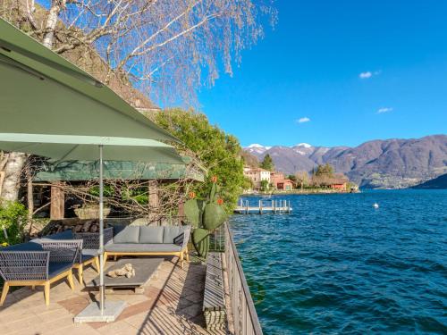 a house on the water with chairs and an umbrella at Villa Casa Silvana by Interhome in Valsolda
