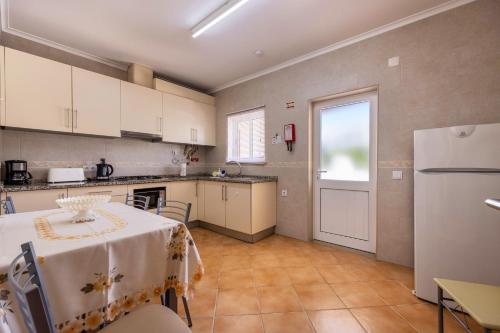 a kitchen with a table and a white refrigerator at Casa Bege T1 in Burgau