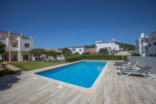 a swimming pool in a villa with two chairs at Casa Bege T1 in Burgau
