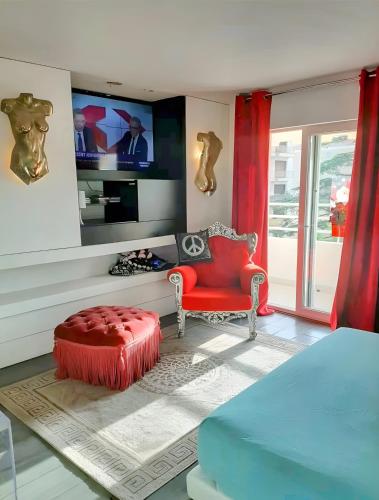 ein Wohnzimmer mit einem roten Sessel und einem Fernseher in der Unterkunft Le Loft in Cannes