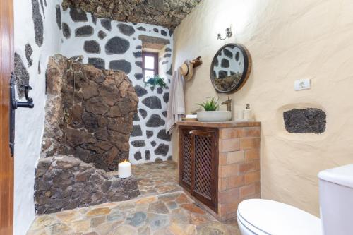 a bathroom with a toilet and a stone wall at El Rincón de Guatisea in San Bartolomé