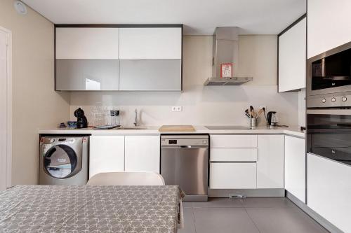 a kitchen with white cabinets and a washer at Sunset Holiday Home in Fernao Ferro