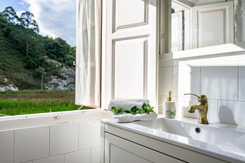 a white kitchen with a sink and a window at La Braña in Bustio