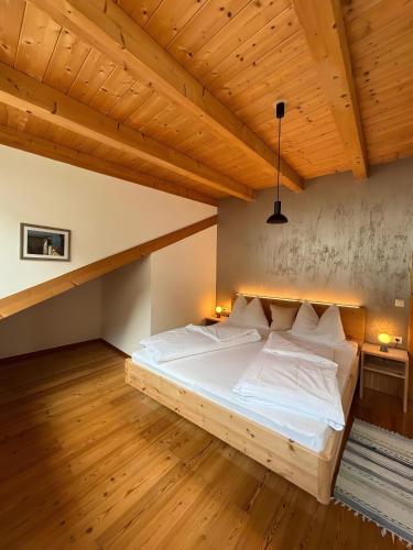 a large bed in a room with a wooden ceiling at Ferienwohnungen Zwick Valarga in Malles Venosta