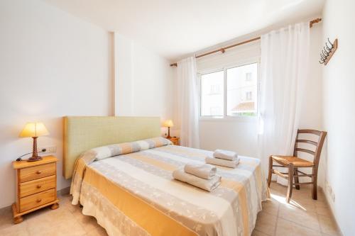 a bedroom with a bed and a chair and a window at Talaia Bajos A in Port de Pollensa