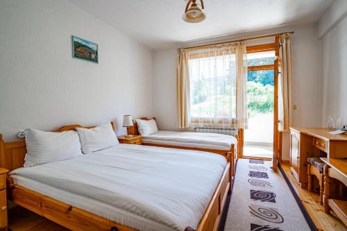 two beds in a room with a window at Yagodina Family Hotel in Yagodina