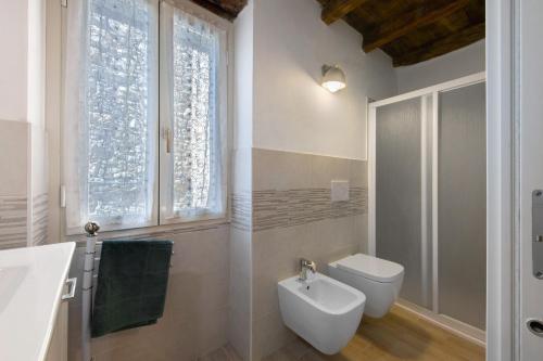 a bathroom with a toilet and a sink and a window at Prima Del Cielo -Appartamento Monti in Esino Lario