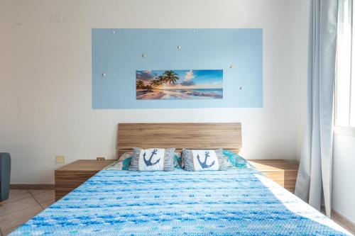 a bedroom with a bed with a blue blanket and pillows at Casa Vacanze 4 Venti in Muravera