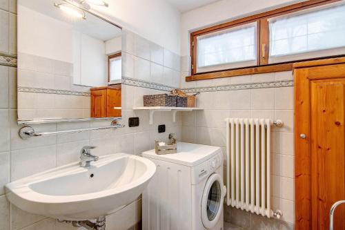 a bathroom with a sink and a washing machine at Residence Larice Bianco App n2 in Campodolcino