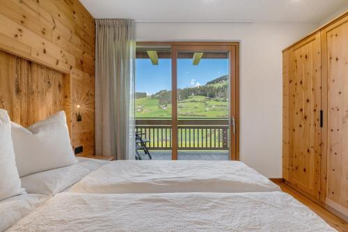 a bedroom with a bed and a large window at Baumannhof Villnöß in Funes