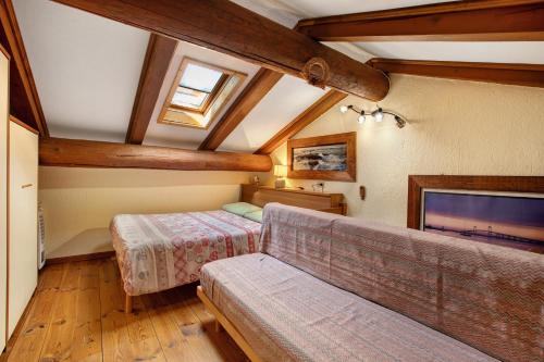 a attic room with a couch and a tv at Eun Tchì Vo - Gignod in Gignod