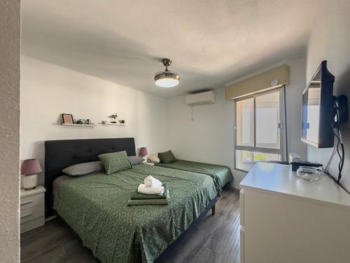 a bedroom with a green bed and a television at Apartamento vistas playa Torrox A73 in Torrox