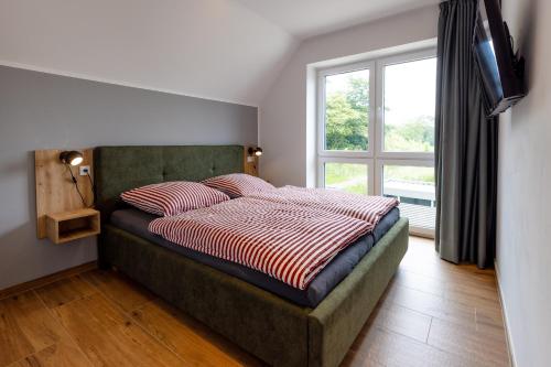 a bedroom with a bed with a window and a television at Ferienhaus Strandnest Dangast in Dangast