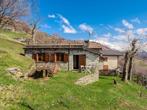 a stone house on a hill with a table and chairs at Chalet Baita Santina by Interhome in Peglio