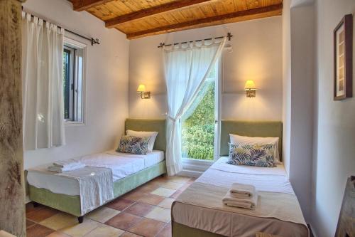 two beds in a room with a window at Villa Ostria in Tsoukalades
