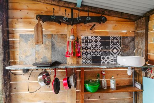 a kitchen with wooden walls and a counter with utensils at Roulotte la casetta Rita in Chambon