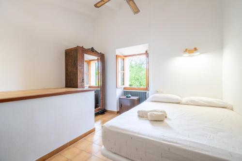 a white bedroom with a bed and a window at Ca'n Repic in Port de Soller