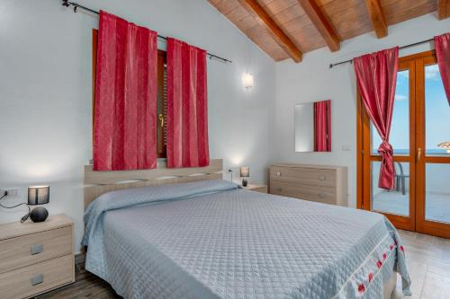 a bedroom with a large bed with red curtains at La finestra sul mare in Budoni