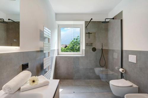a bathroom with a sink and a toilet and a window at Haus Weinblick Apt 3 in Magrè allʼ Adige