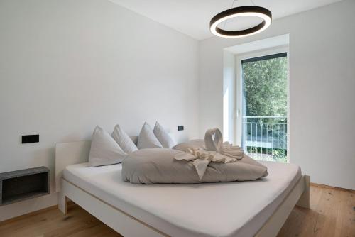 a white bedroom with a bed with a large window at Haus Weinblick Apt 3 in Magrè allʼ Adige
