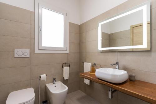 a bathroom with a sink and a toilet and a mirror at Le scuderie 9 in Galatone