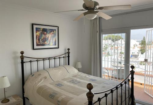 a bedroom with a bed with a ceiling fan and a window at Salida Del Sol in Nerja