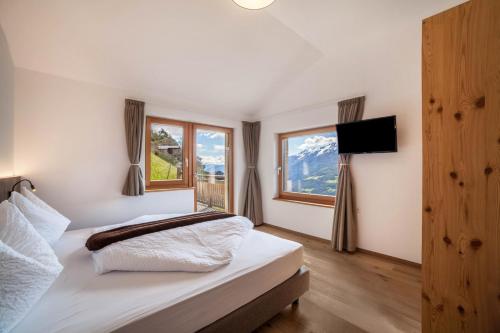 a bedroom with a bed with a television and windows at Flatschhof - Apartment Cevedale in Kastelbell-Tschars
