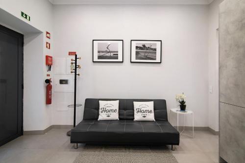 a black couch in a white room with two pillows at Casa Anzol in Fuzeta