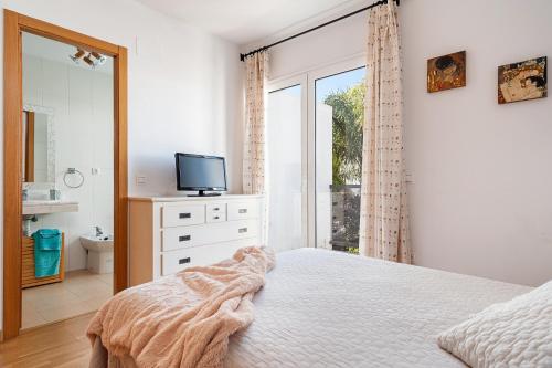 a bedroom with a bed and a tv and a window at Casa Alena in Conil de la Frontera