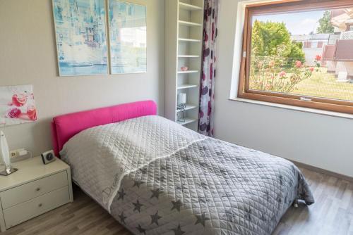 a bedroom with a bed with a pink headboard and a window at Haus Jäschke in Bremerhaven