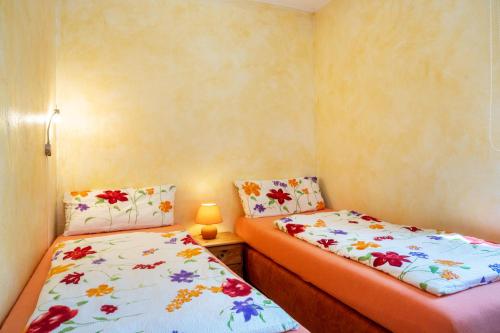 Zwei Einzelbetten in einem kleinen Zimmer mit Blumen in der Unterkunft Apartment Sonnengärtchen in Blankenburg