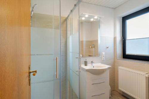 a bathroom with a sink and a glass shower at Gästehaus Vogel in Horumersiel