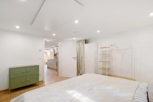 a white bedroom with a bed and a green cabinet at Ferienwohnung Apfelwiese in Meßstetten