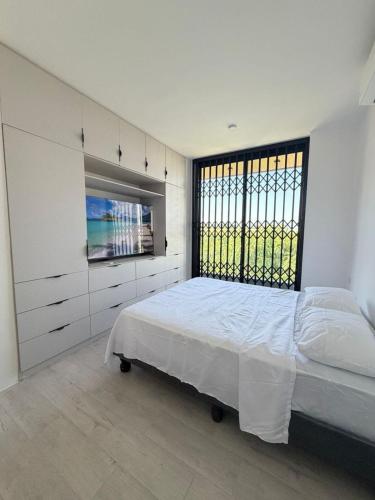 a white bedroom with a bed and a large window at Vive Manta como nunca antes! in Manta