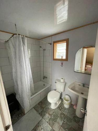a bathroom with a toilet and a tub and a sink at Cabañas Isidora in Dalcahue