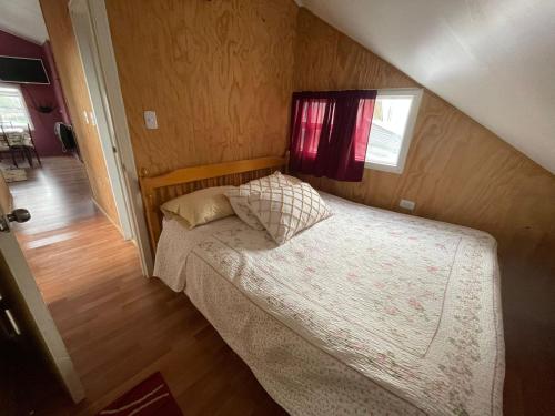 a small bedroom with a bed with a window at Cabañas Isidora in Dalcahue