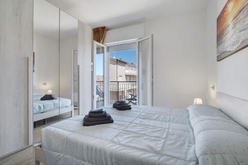 a white bedroom with a large bed and a balcony at Villa Trentina in Lido di Jesolo