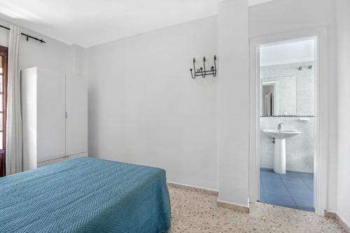 a white bedroom with a bed and a sink at Chipiona Centro y Playa in Chipiona