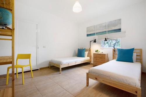 a bedroom with two beds and a chair in it at Abundia House in Caleta De Fuste