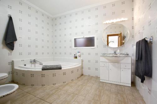 a bathroom with a tub and a sink and a mirror at Abundia House in Caleta De Fuste
