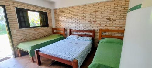 a small room with two beds and a window at Chalés Do Sol in Boracéia