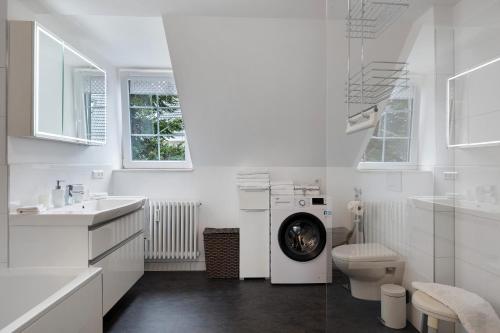 a white bathroom with a washing machine and a toilet at Ferienwohnung Alte Münz in Müllheim
