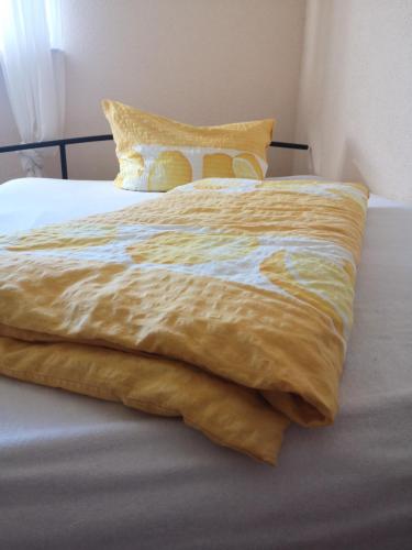 a bed with a yellow blanket on top of it at Klein aber Fein in Gottmadingen