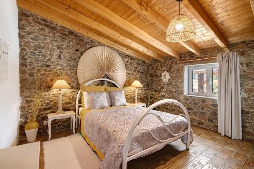 a bedroom with a bed and a stone wall at Quinta do Silêncio in Tavira