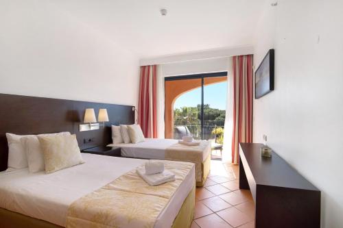 a hotel room with two beds and a balcony at Apartamento T2 Vilasol Morgadinho in Vilamoura