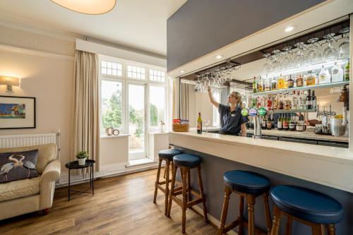 a woman standing behind a bar with blue stools at Northfield Hotel in Minehead